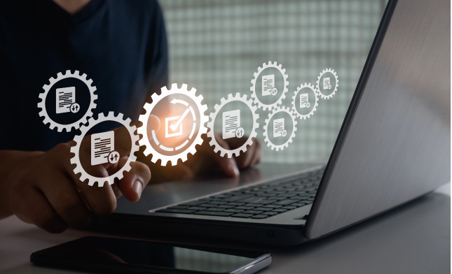 A person working on a laptop with graphic icons of gears and documents representing data management or workflow automation.